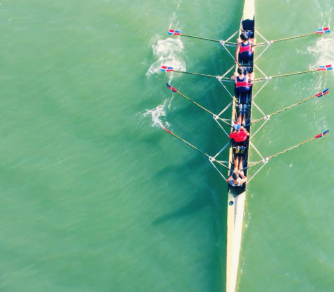 Bühnenbild mit türkisem Wasser und einem Sport-Ruderboot auf dem Wasser in Bewegung